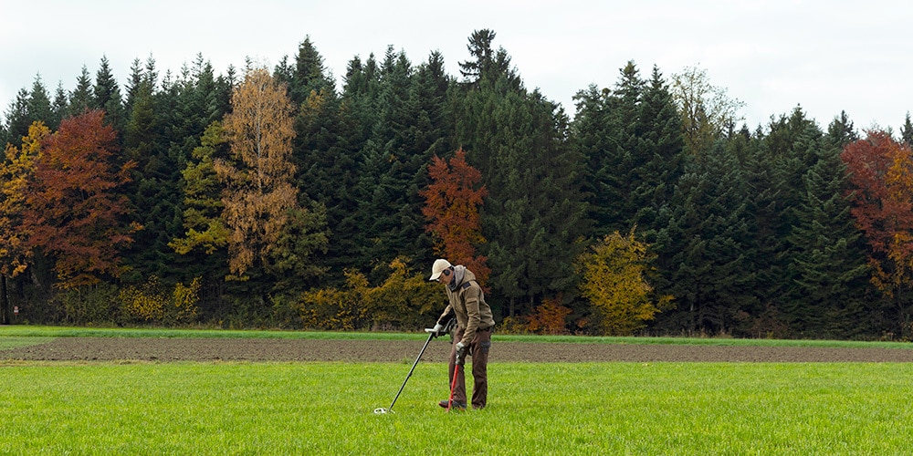 Ein freiwilliger Prospektorant auf der Suche mit einem Metall-Detektor nach archäologischen Funden auf einem Feld